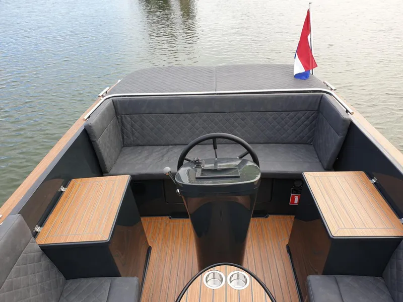 Slide: The Image of 2023 Maxima 620 Retro boat interior with steering wheel and seating, on calm water. - 16