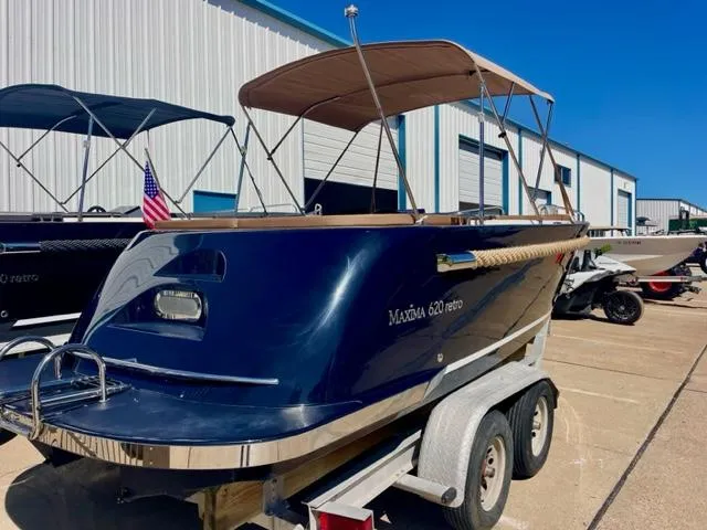 Slide: The Image of 2023 Maxima 620 Retro boat on trailer, blue hull, tan canopy, parked outside. - 5