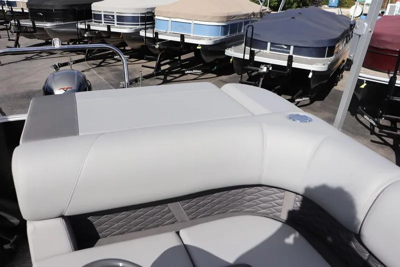 Slide: The Image of 2024 Bennington 20 SL pontoon boat with cushioned seating, docked among covered boats. - 10