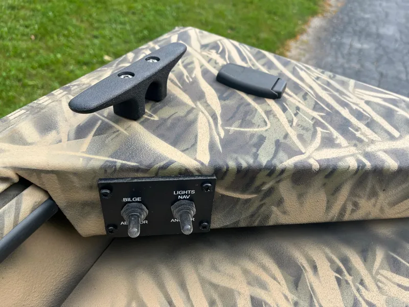 Slide: The Image of 2024 Lowe Roughneck 1660 boat controls and cleat on camo deck. - 12