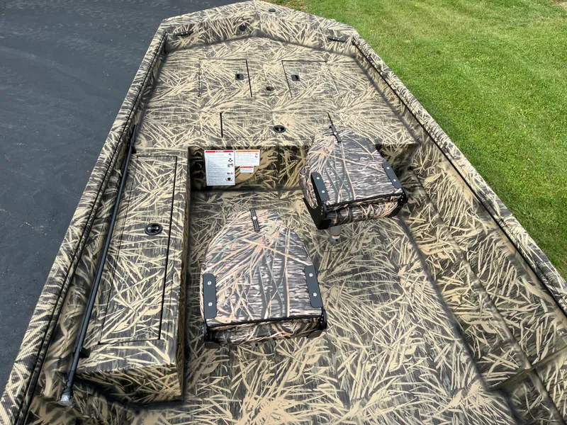 Slide: The Image of 2024 Lowe Roughneck 1660 boat interior with camouflage design, featuring storage compartments and seating. - 5