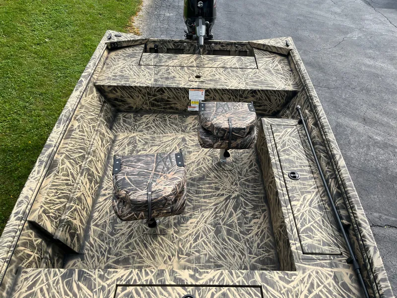 Slide: The Image of 2024 Lowe Roughneck 1660 camo fishing boat interior with seats and storage compartments. - 7