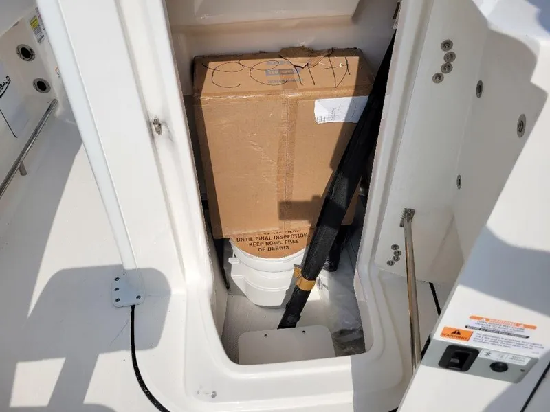 Slide: The Image of Storage compartment of 2024 Robalo 250 CC boat with cardboard box and equipment. - 13