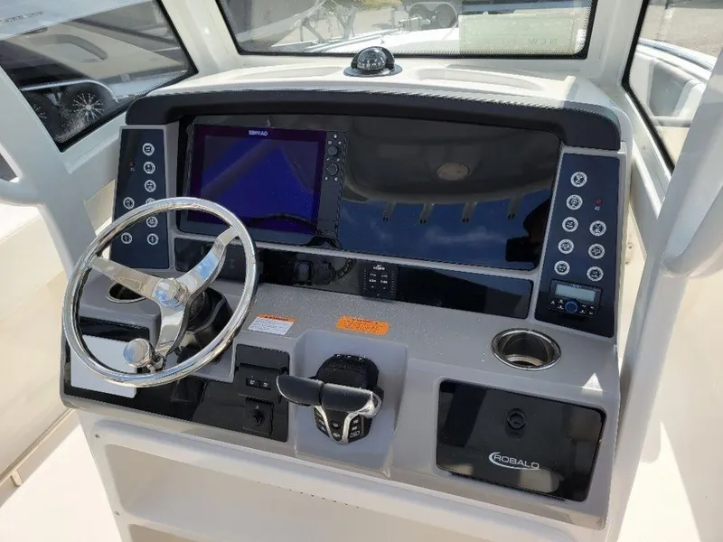 Slide: The Image of 2024 Robalo 250 CC boat dashboard with steering wheel and navigation controls. - 17