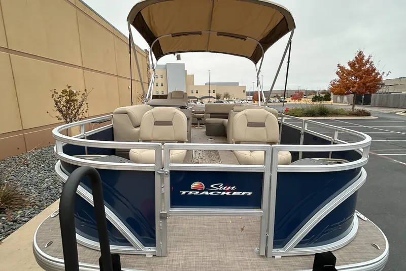 Slide: The Image of 2024 Sun Tracker Fishin' Barge 22 XP3 pontoon boat with canopy in parking lot. - 2