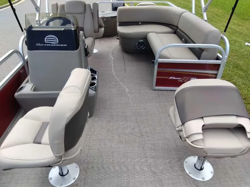 Slide: The Image of 2024 Sun Tracker Bass Buggy 18 DLX pontoon boat interior with seating and steering console. - 2