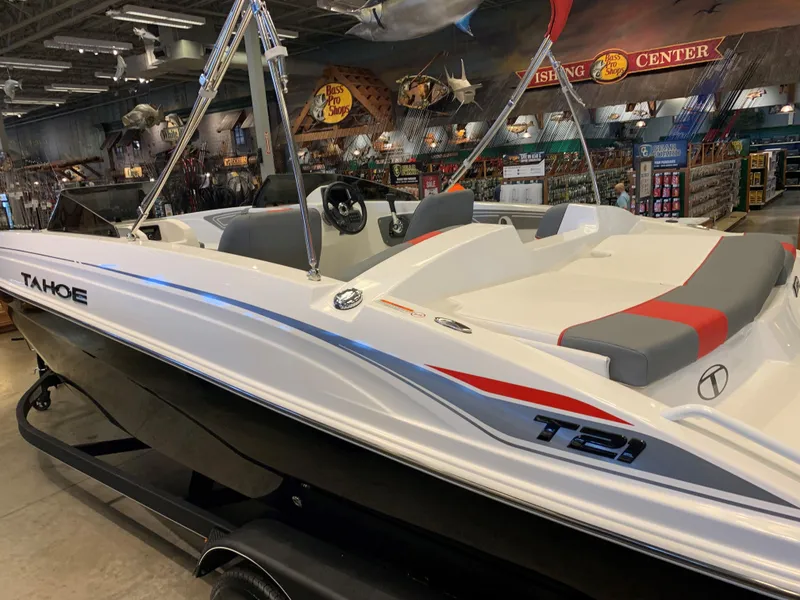 Slide: The Image of 2024 Tahoe T21 boat displayed in a showroom with fishing gear. - 0