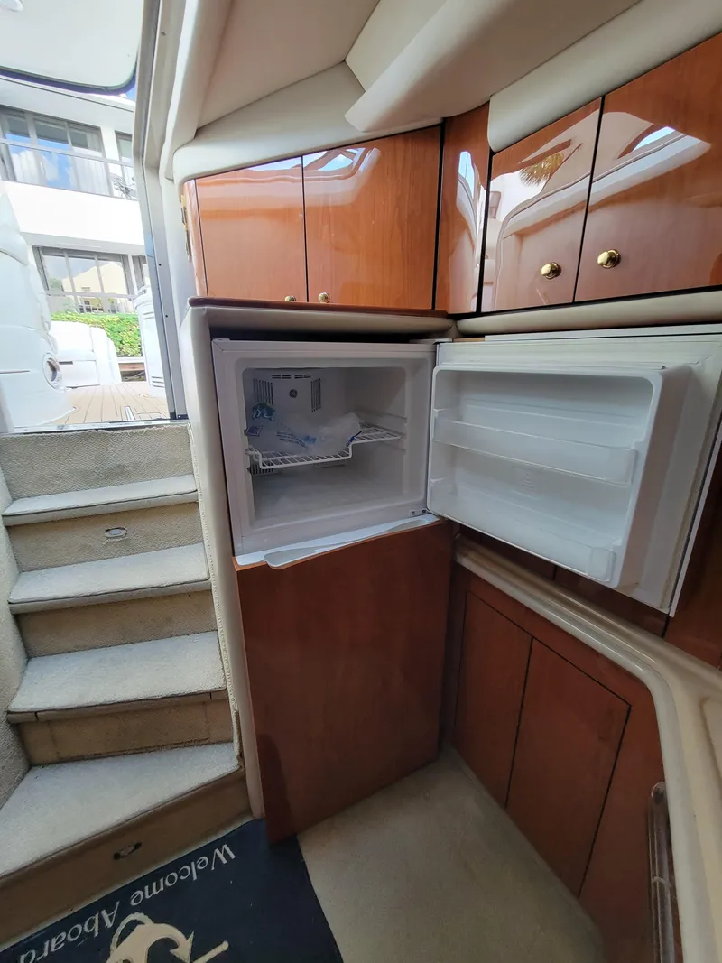 Slide: The Image of 2000 Sea Ray 540 Sundancer interior with open refrigerator and wooden cabinetry. - 27