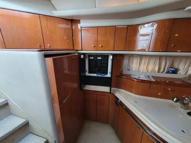 Slide: The Image of Interior of 2000 Sea Ray 540 Sundancer yacht with wooden cabinets and kitchen area. - 26