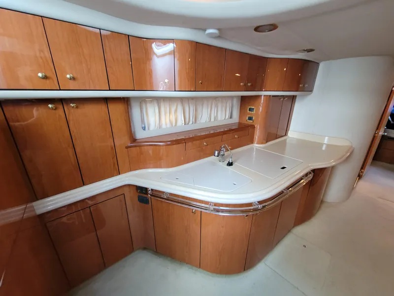 Slide: The Image of 2000 Sea Ray 540 Sundancer yacht kitchen with wooden cabinets and white countertops. - 28