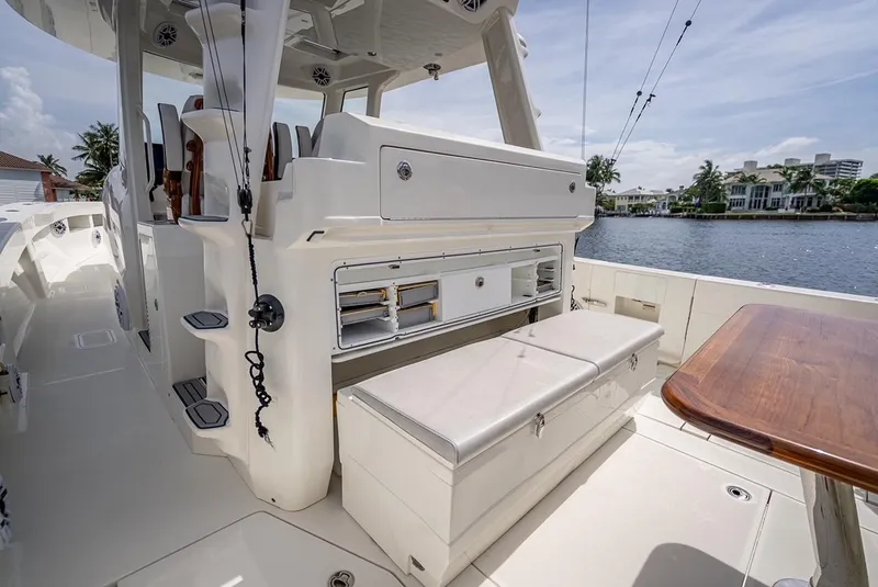 Slide: The Image of 2021 SeaVee 450z boat interior with seating and storage, docked by waterfront homes. - 7