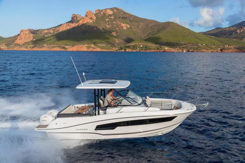 Slide: The Image of 2024 Jeanneau Leader 9.0 WA S2 cruising on open water with scenic mountain backdrop. - 2