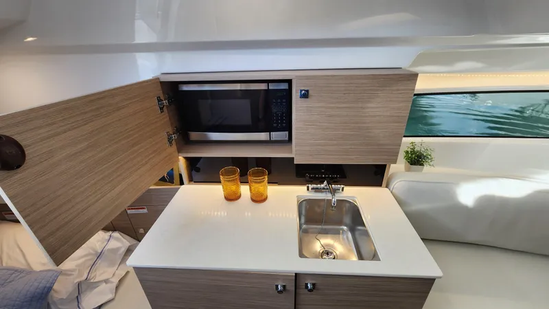 Slide: The Image of 2024 Jeanneau Leader 9.0 WA S2 interior kitchen with sink, microwave, and storage cabinets. - 29