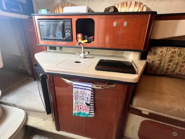 Slide: The Image of 2005 Sea Ray 260 Sundancer interior kitchen with microwave, sink, and storage. - 22