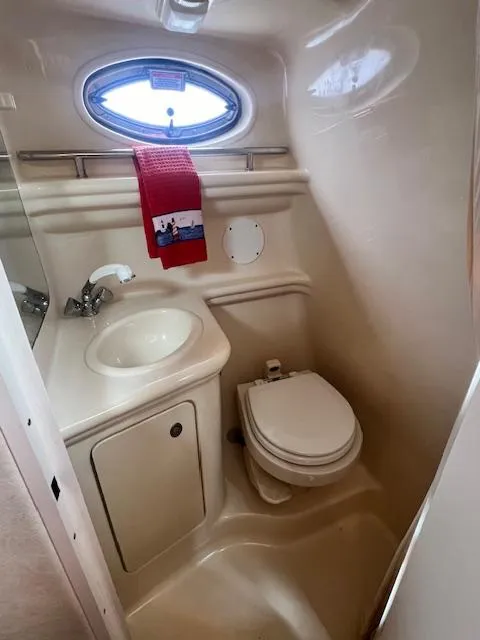 Slide: The Image of 2005 Sea Ray 260 Sundancer bathroom with sink, toilet, and porthole window. - 24