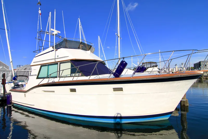 The Image of 1977 Hatteras 37 Convertible yacht docked at a marina on a sunny day. - 0