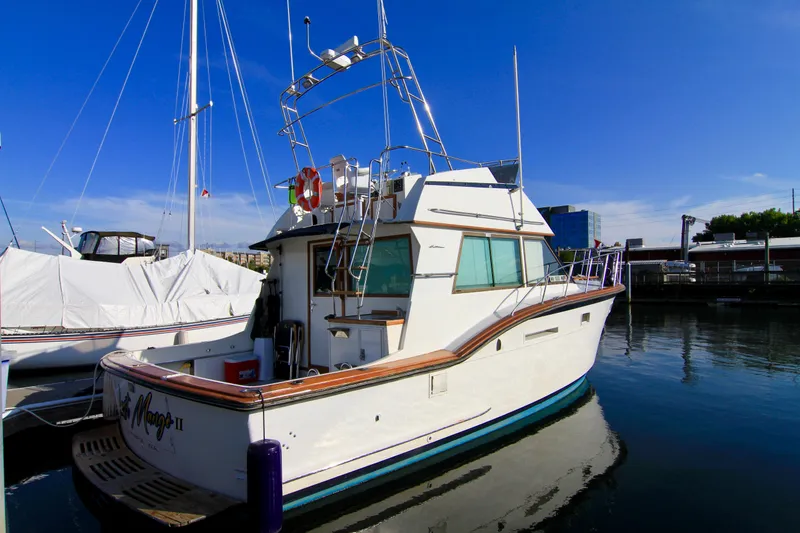 Slide: The Image of 1977 Hatteras 37 Convertible yacht docked at marina under clear blue sky. - 2
