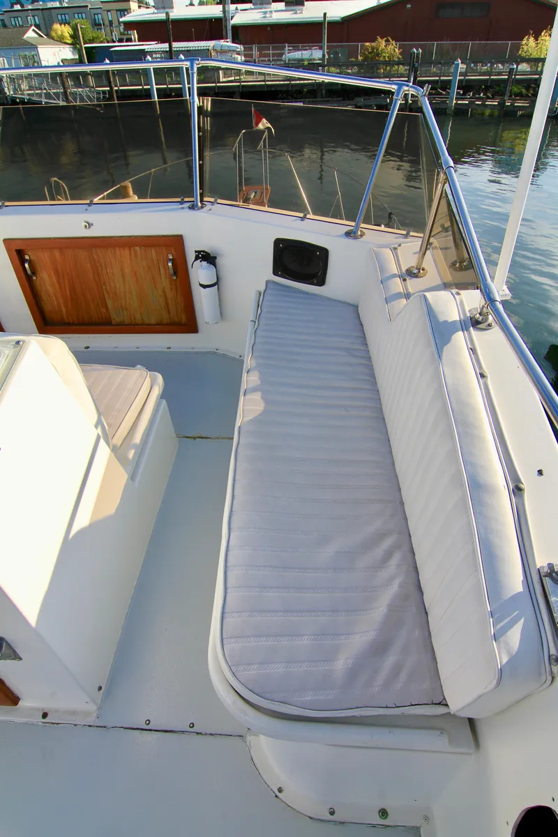 Slide: The Image of 1977 Hatteras 37 Convertible boat deck with cushioned seating and wooden storage. - 25