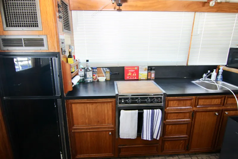Slide: The Image of 1977 Hatteras 37 Convertible kitchen with wooden cabinets and black countertops. - 48