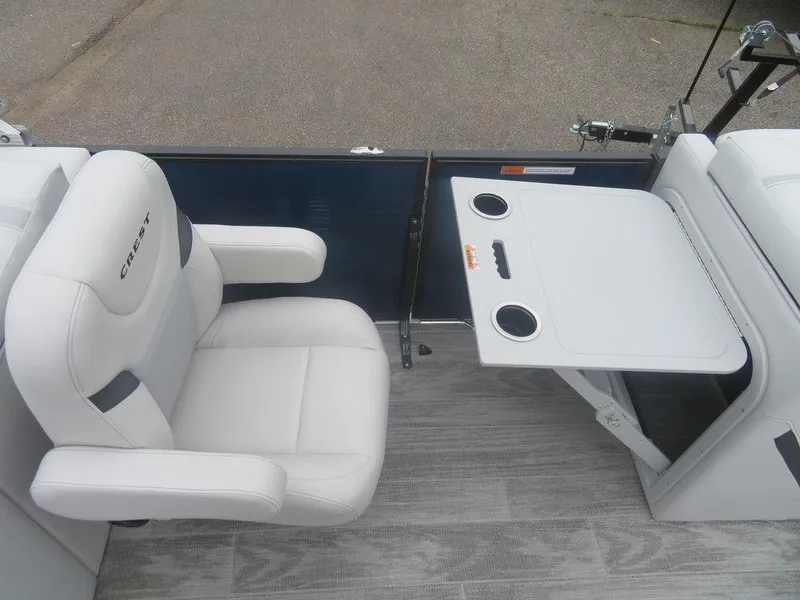 Slide: The Image of 2024 Crest Classic LX 240 SLRC boat interior with white seating and foldable table. - 8