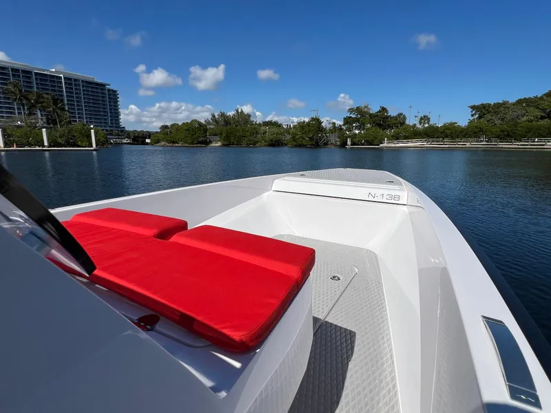 Slide: The Image of 2021 Goldfish 23 Tender boat with red seating, on a calm waterway under a clear blue sky. - 26
