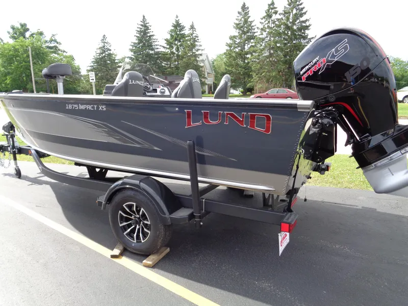 Slide: The Image of 2024 Lund 1875 Impact XS SS boat on trailer, parked outdoors. - 13