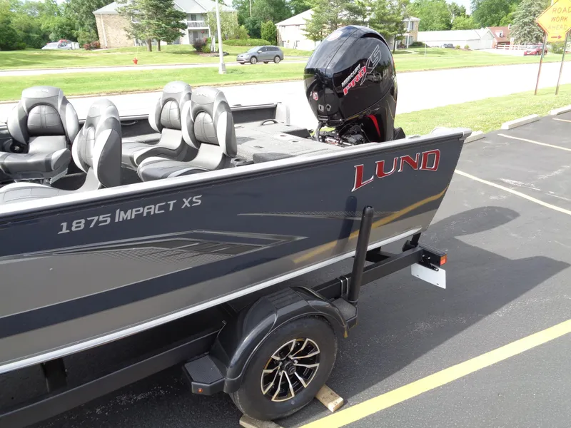 Slide: The Image of 2024 Lund 1875 Impact XS SS boat on trailer, parked in a lot. - 2