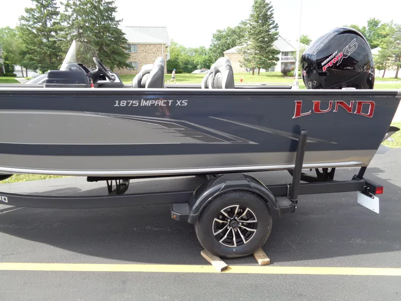 Slide: The Image of 2024 Lund 1875 Impact XS SS boat on trailer, parked outdoors. - 3