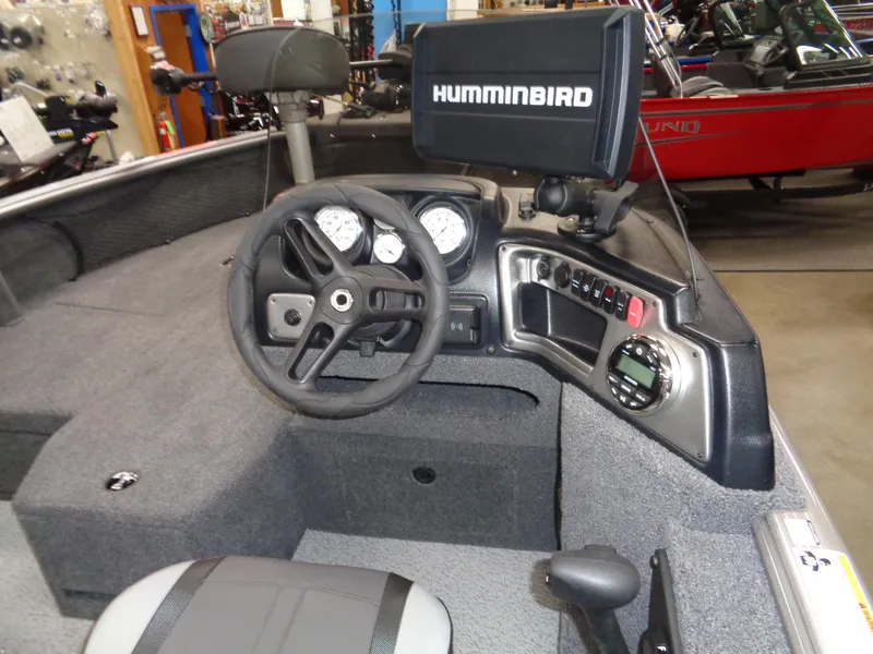 Slide: The Image of 2024 Lund 1875 Impact XS SS fishing boat in showroom, black exterior, multiple seats. - 11