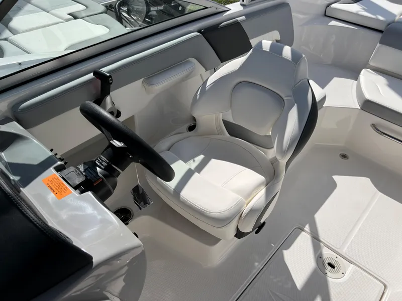 Slide: The Image of 2023 Chaparral 23 SSi OB boat cockpit with white captain's chair and steering wheel. - 12