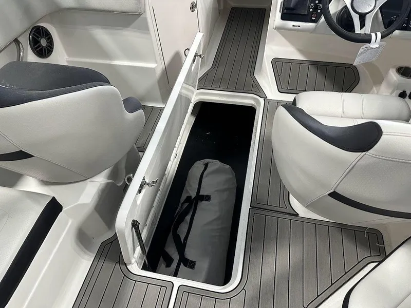 Slide: The Image of 2024 Sea Ray 210 SPX OB interior storage compartment with gray flooring and white seats. - 11
