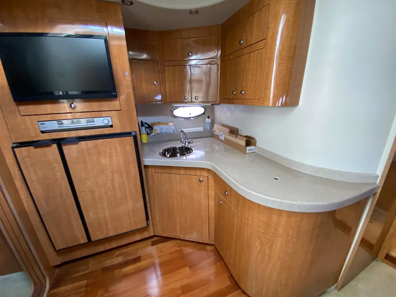 Slide: The Image of 2004 Regal 3860 Commodore yacht kitchen with wood cabinets, TV, and sink. - 16