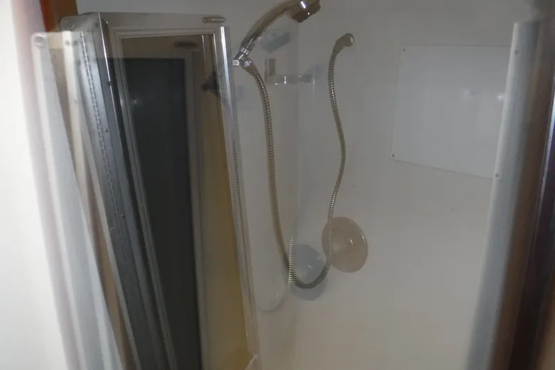 Slide: The Image of Shower area inside 1989 Viking 41 Sportfish Convertible boat, featuring a flexible showerhead. - 50