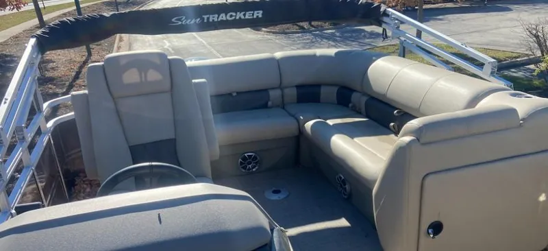 Slide: The Image of 2024 Sun Tracker Party Barge 20 DLX interior with beige seating and steering console. - 5