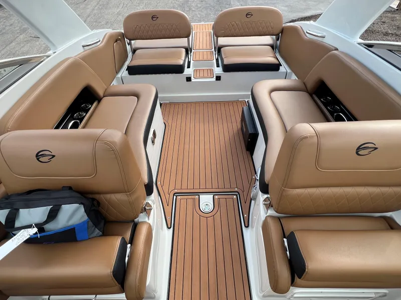 Slide: The Image of 2024 Crownline E305 boat interior with tan leather seating and wooden flooring. - 2