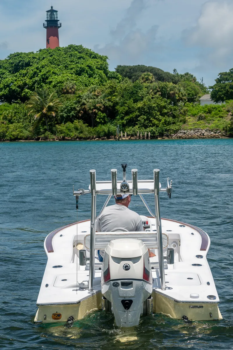 Slide: The Image of Man driving 2017 Custom Envi Redfisher boat near a lighthouse on a sunny day. - 2