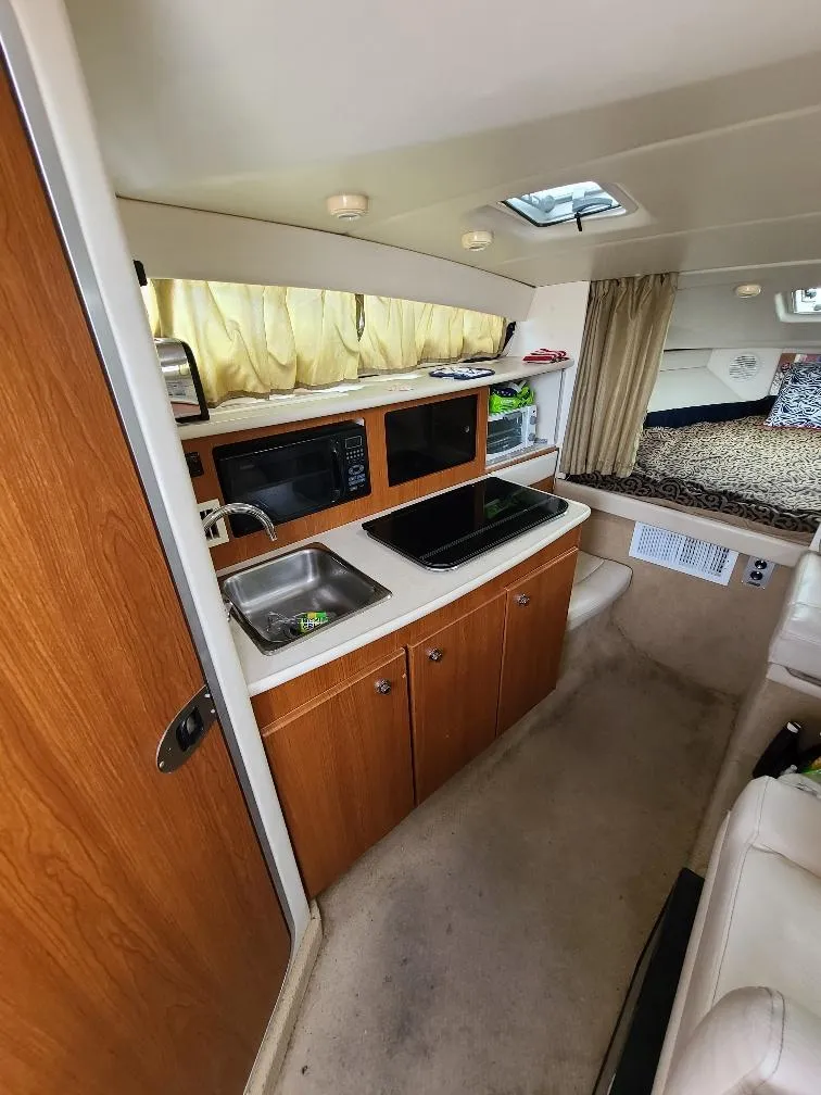 Slide: The Image of 2003 Bayliner 285 Ciera interior with kitchenette, sink, microwave, and cozy sleeping area. - 16