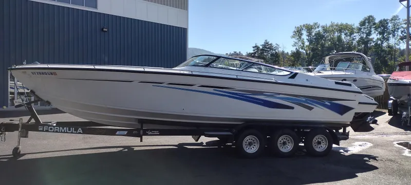 Slide: The Image of 1991 Formula 272 SR1 speedboat on a trailer, white with blue accents, parked outdoors. - 3