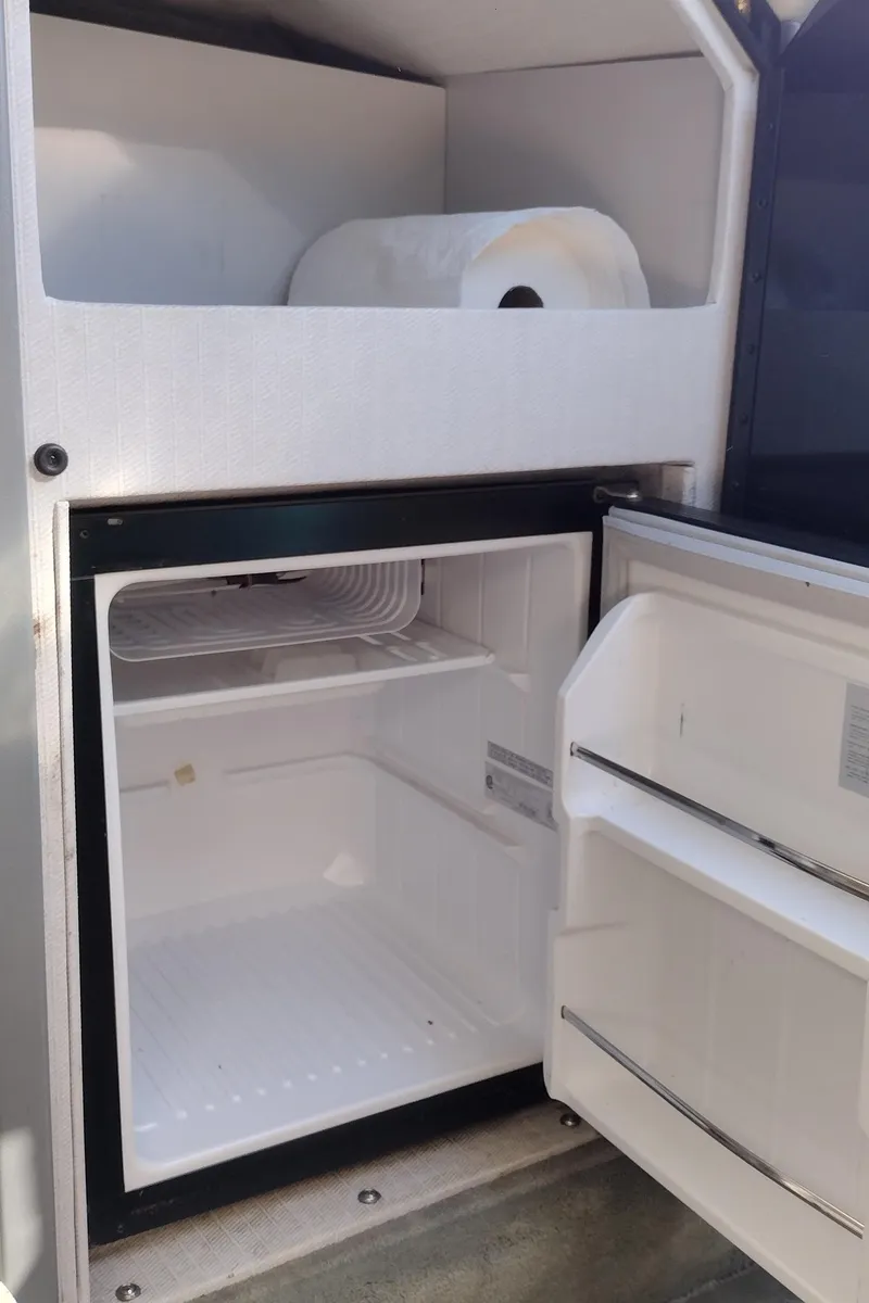Slide: The Image of Open mini fridge in a 1991 Formula 272 SR1 boat with paper towel storage above. - 33