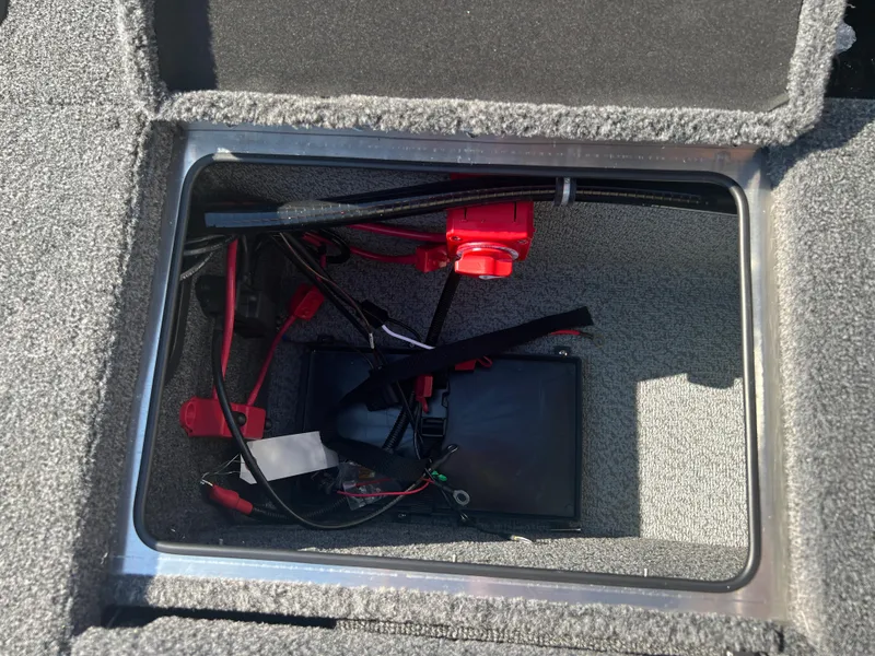 Slide: The Image of 2024 Lund 1875 Pro-V Bass XS storage compartment with wiring and battery components. - 24
