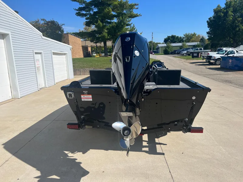 Slide: The Image of 2024 Lund 1875 Pro-V Bass XS boat with outboard motor, parked on a concrete driveway. - 5