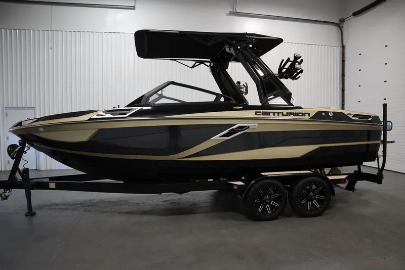 Slide: The Image of 2024 Centurion Ri230 boat in a showroom, featuring sleek black and gold design on a trailer. - 1