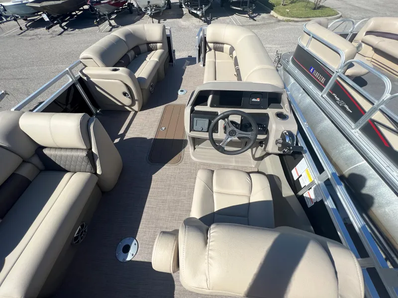 Slide: The Image of 2024 Sun Tracker SportFish 22 XP3 pontoon boat interior with beige seating and steering console. - 4