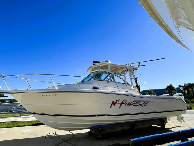 Slide: The Image of 2005 Pursuit 3070 Offshore boat on a trailer under a clear blue sky. - 0
