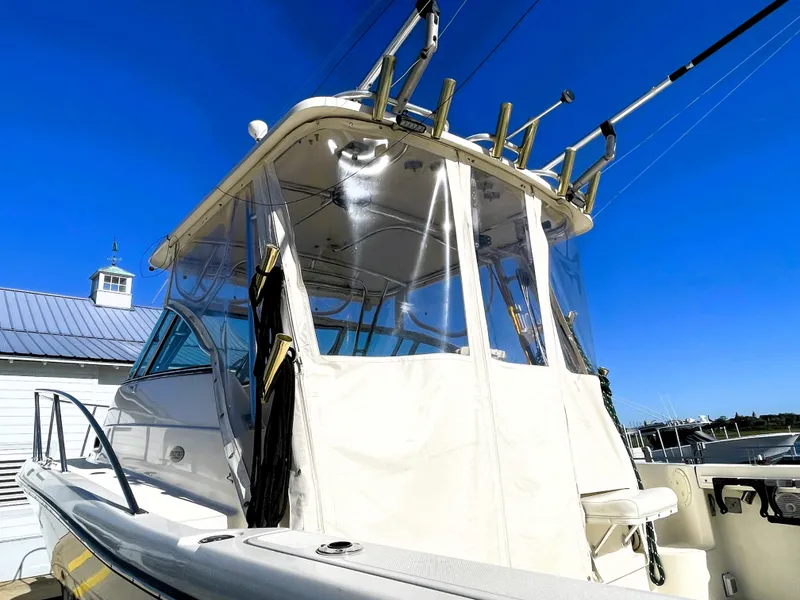 Slide: The Image of 2005 Pursuit 3070 Offshore boat with clear enclosure and fishing rod holders. - 21