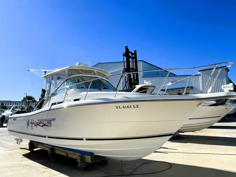 Slide: The Image of 2005 Pursuit 3070 Offshore boat on dry dock under clear blue sky. - 3
