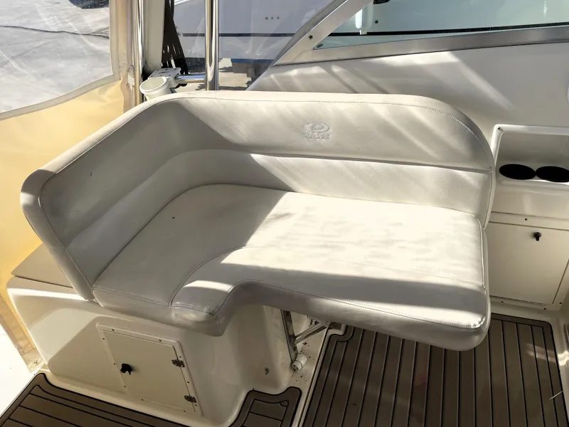 Slide: The Image of 2005 Pursuit 3070 Offshore boat interior seating area with white cushioned bench. - 40