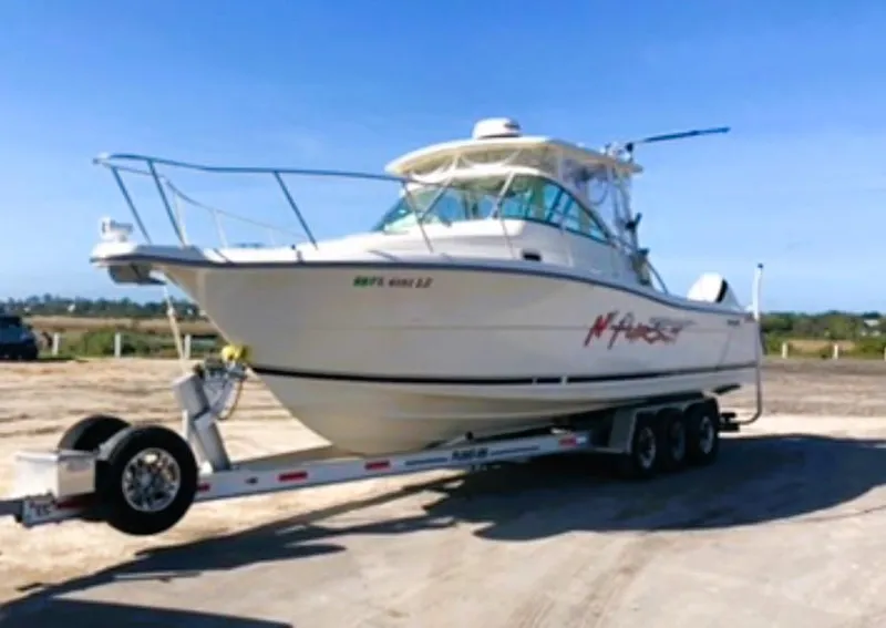 Slide: The Image of 2005 Pursuit 3070 Offshore boat on a trailer in a sunny outdoor setting. - 6