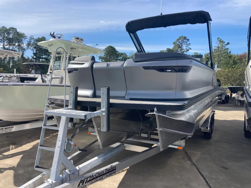 The Image of 2024 Manitou Explorer 24 Switchback 24 MAX Trifold Stealth pontoon boat on trailer. - 0