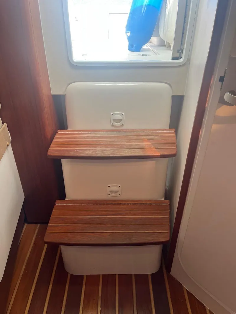 Slide: The Image of 2000 Pursuit 3000 Express boat interior with wooden steps and white walls. - 12